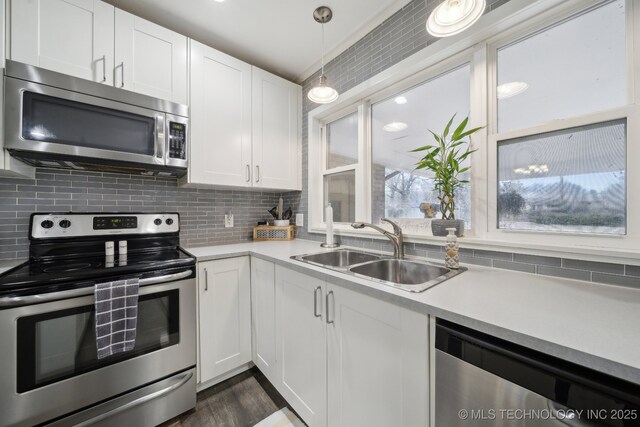 kitchen with stainless steel appliances, white cabinetry, sink, and pendant lighting