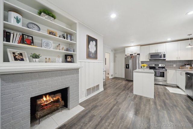 kitchen with decorative light fixtures, dark hardwood / wood-style flooring, a kitchen island, stainless steel appliances, and white cabinets