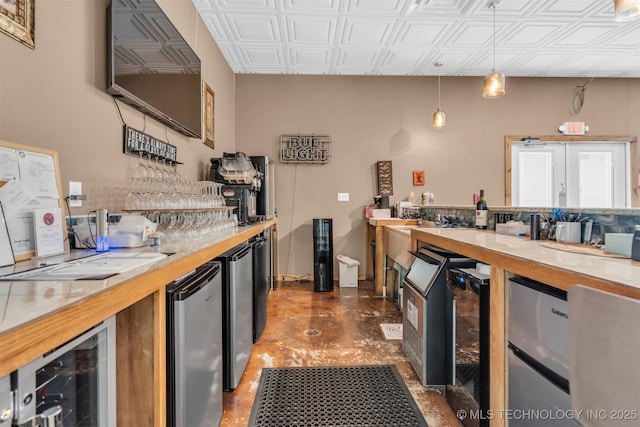 kitchen with wine cooler, fridge, hanging light fixtures, and stainless steel refrigerator