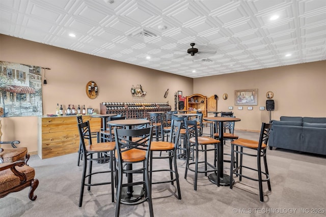 dining room featuring indoor bar and light colored carpet