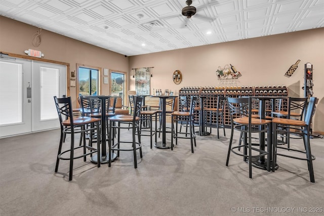 carpeted dining space featuring bar and french doors