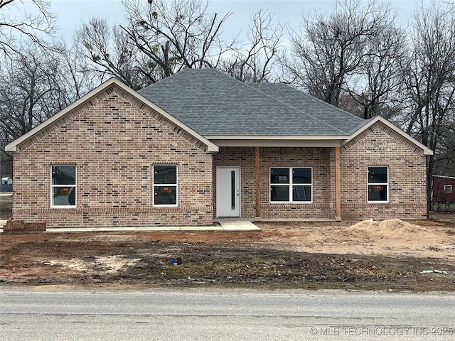 view of front of house with a shingled roof and brick siding