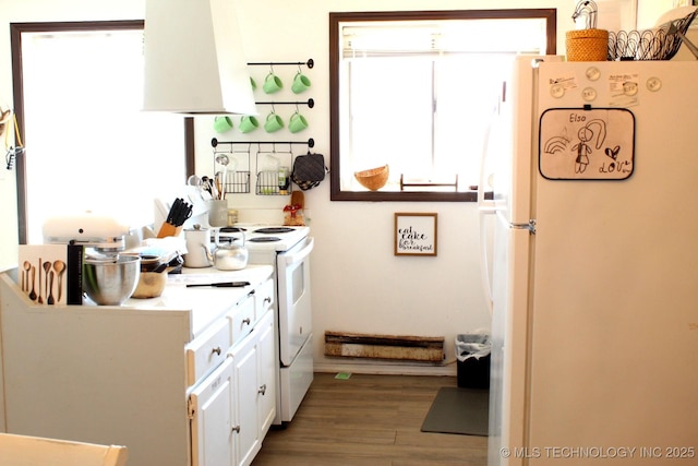 interior space with white cabinets, white appliances, a wealth of natural light, and exhaust hood