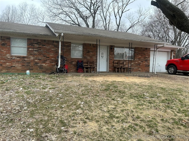 single story home with a garage, covered porch, and a front yard