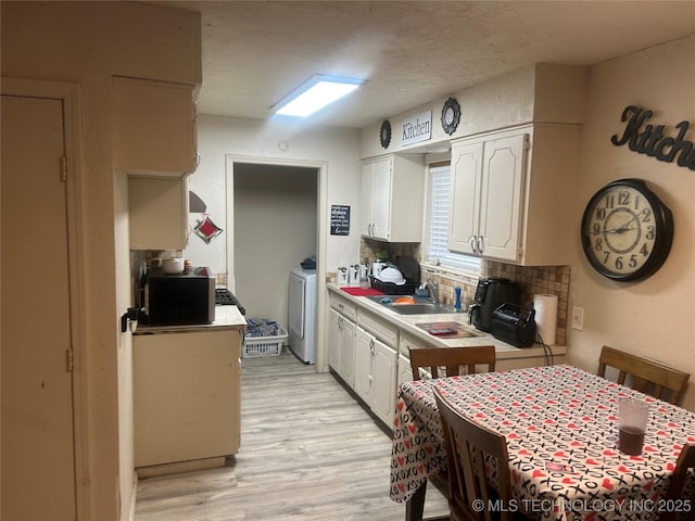 kitchen featuring sink, white cabinetry, light hardwood / wood-style flooring, a textured ceiling, and decorative backsplash