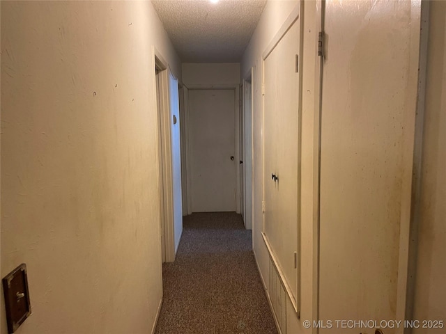 corridor with dark carpet and a textured ceiling