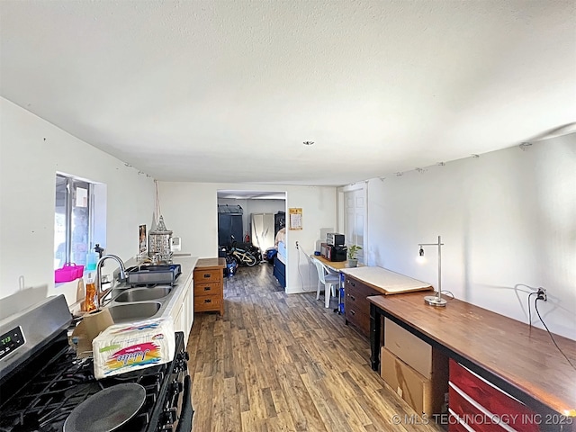 kitchen featuring dark hardwood / wood-style floors, sink, stainless steel gas range, and a textured ceiling