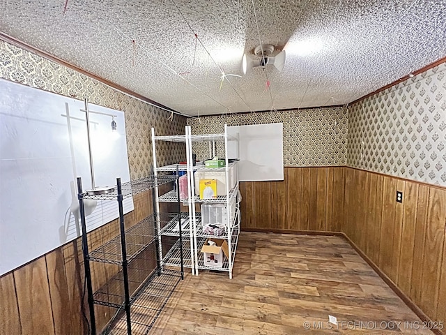 interior space with crown molding, hardwood / wood-style floors, a textured ceiling, and wood walls