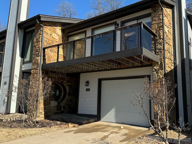 view of front of house with driveway, stone siding, and an attached garage