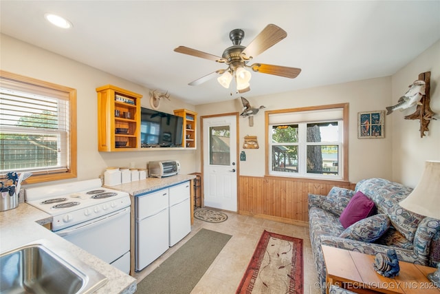 kitchen featuring ceiling fan, wooden walls, white electric stove, and white cabinets