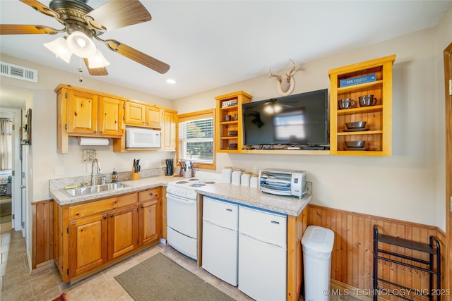 kitchen with sink, white appliances, ceiling fan, and wood walls