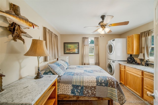 bedroom with ceiling fan, stacked washer and dryer, and tile patterned flooring