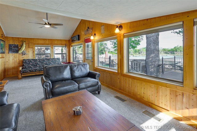 living room with lofted ceiling, carpet flooring, and wood walls