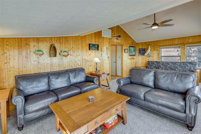 carpeted living room with ceiling fan, vaulted ceiling, and wood walls