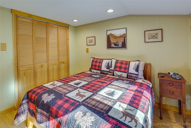 bedroom with vaulted ceiling, light wood-type flooring, and a closet