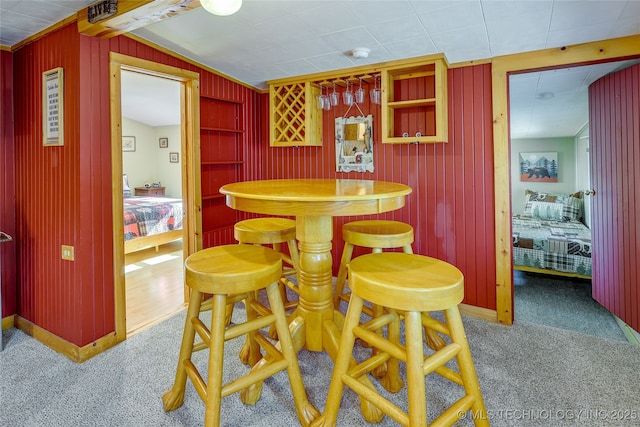 dining space with bar area, wooden walls, and carpet floors