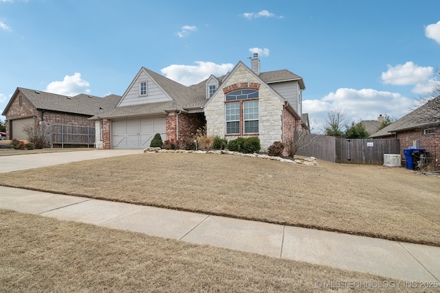 view of front of home with a garage, central AC, and a front lawn