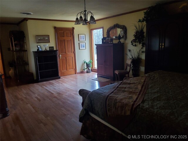 bedroom featuring hardwood / wood-style flooring, ornamental molding, and a chandelier