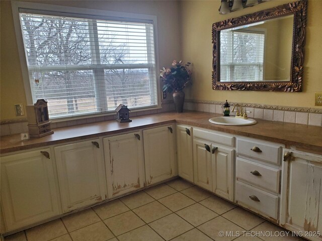 kitchen with sink, light tile patterned floors, and a healthy amount of sunlight