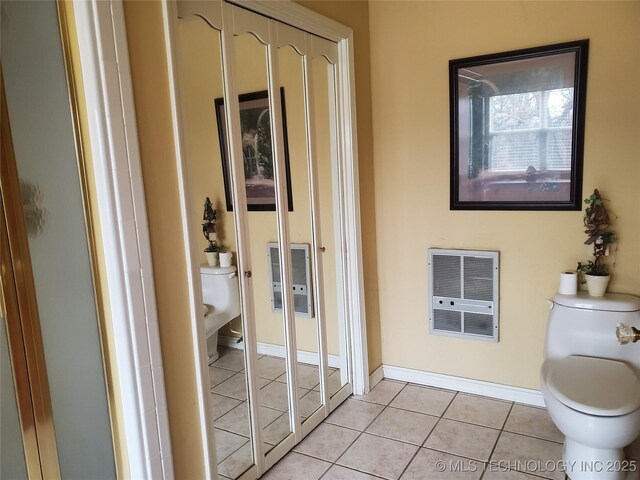 bathroom featuring tile patterned flooring, heating unit, and toilet