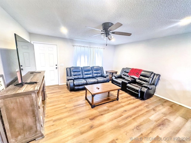 living room featuring ceiling fan, light hardwood / wood-style flooring, and a textured ceiling