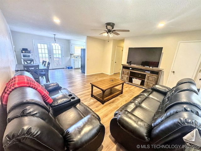 living room with ceiling fan, a textured ceiling, and light wood-type flooring