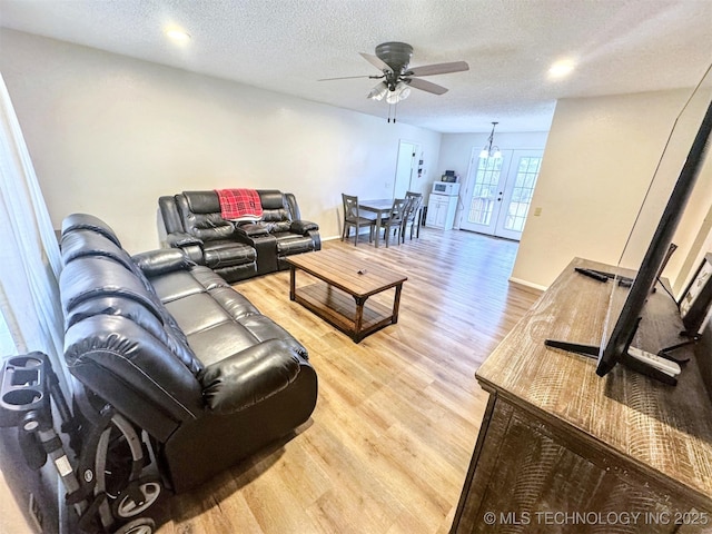 living room featuring ceiling fan, a textured ceiling, light wood-type flooring, and french doors