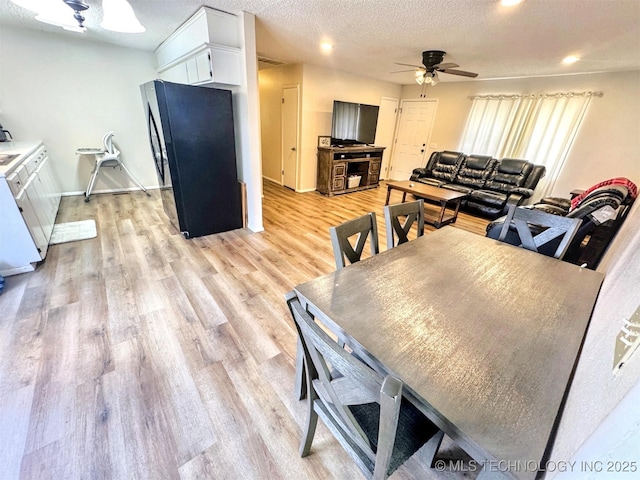 dining space with a textured ceiling, ceiling fan, and light wood-type flooring