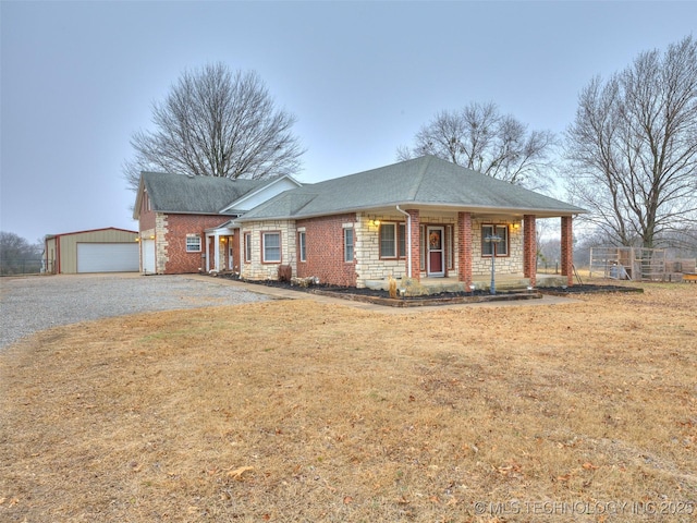 ranch-style home with an outbuilding, a porch, a garage, and a front lawn