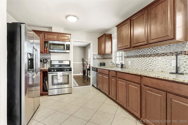 kitchen featuring sink, stainless steel appliances, light stone countertops, and backsplash