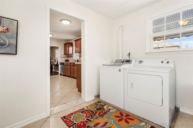 laundry room featuring washing machine and dryer, sink, and light tile patterned floors