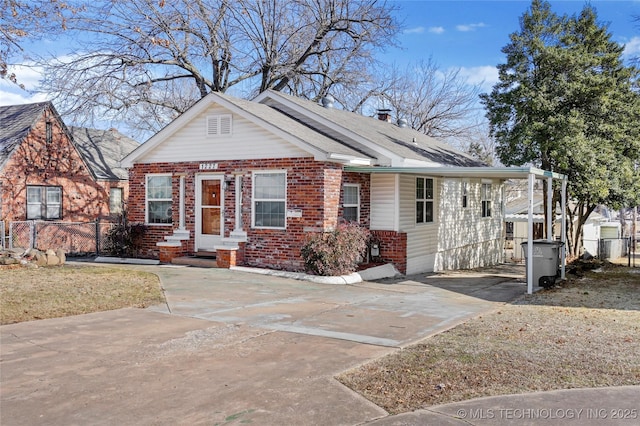 view of front of property with concrete driveway, fence, brick siding, and a shingled roof