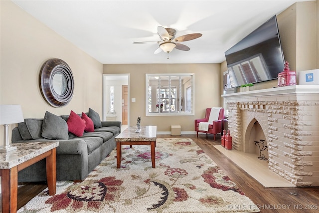 living room featuring hardwood / wood-style flooring, a brick fireplace, and ceiling fan