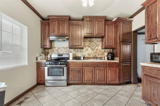 kitchen featuring stainless steel gas stove, sink, tasteful backsplash, and ornamental molding