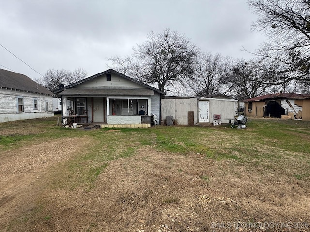 rear view of property with covered porch and a lawn