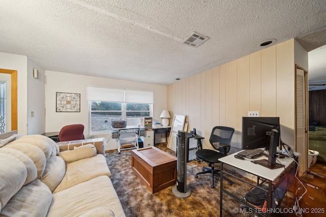 home office with a textured ceiling and dark colored carpet