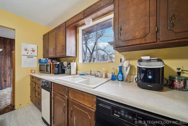 kitchen with dark brown cabinetry, sink, a textured ceiling, and black dishwasher