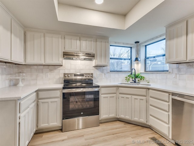 kitchen featuring stainless steel appliances, light countertops, under cabinet range hood, and white cabinetry