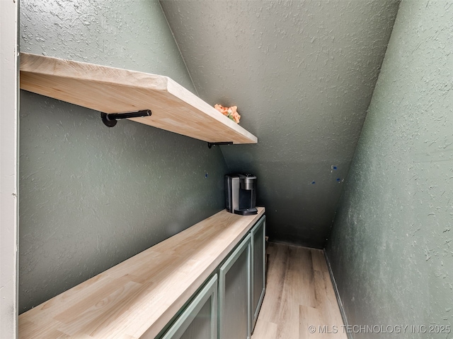 bar featuring a textured wall and light wood-style flooring