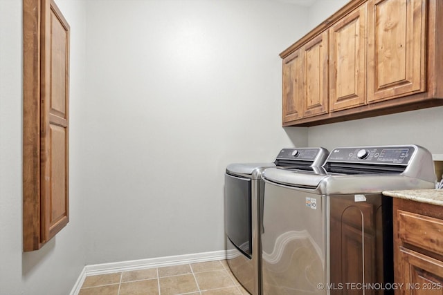 laundry area with cabinets, light tile patterned flooring, and washing machine and clothes dryer