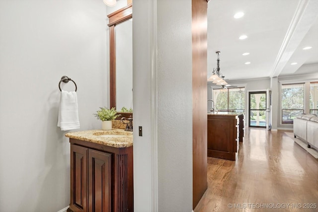 bathroom with a sink, two vanities, wood finished floors, and recessed lighting
