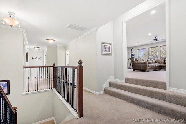 hall with visible vents, carpet floors, baseboards, and ornamental molding