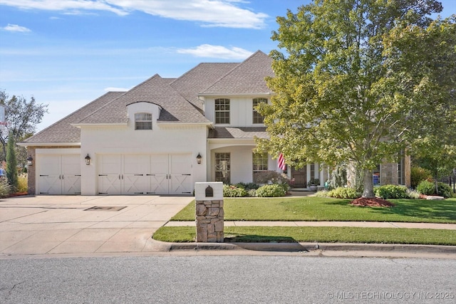 view of front of property featuring a front lawn, a garage, and roof with shingles