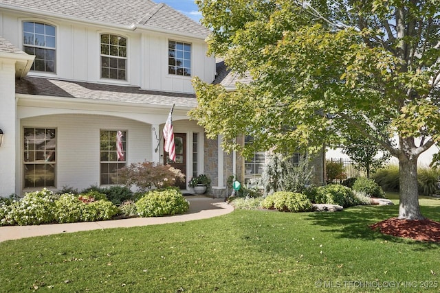 view of front of home featuring board and batten siding, a front yard, and roof with shingles