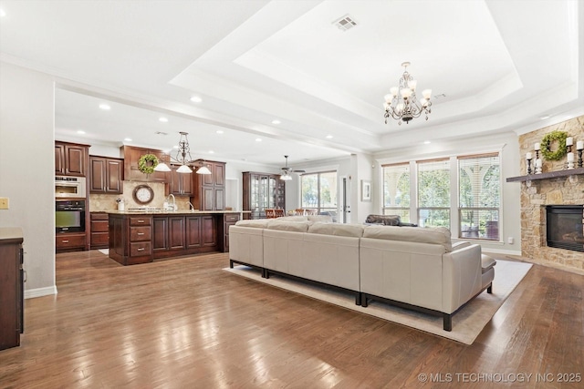 living area featuring a raised ceiling, plenty of natural light, a fireplace, and visible vents