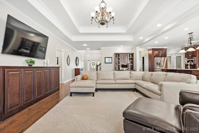 living area featuring dark wood-style floors, a tray ceiling, recessed lighting, crown molding, and a chandelier