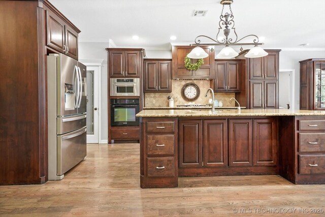 kitchen with visible vents, a sink, stainless steel refrigerator with ice dispenser, crown molding, and decorative light fixtures