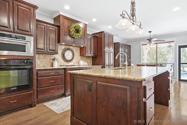 kitchen featuring a sink, backsplash, double oven, and ornamental molding