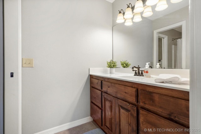 bathroom with vanity, tile patterned floors, baseboards, and a chandelier