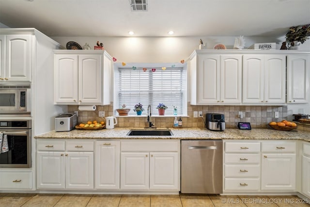 kitchen featuring sink, white cabinetry, light stone counters, stainless steel appliances, and backsplash